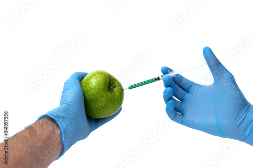 Pesticides and nitrates are injected into a apple with a syringe. Gmo concept