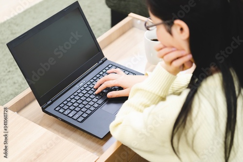 部屋でノートパソコンを使う女性
