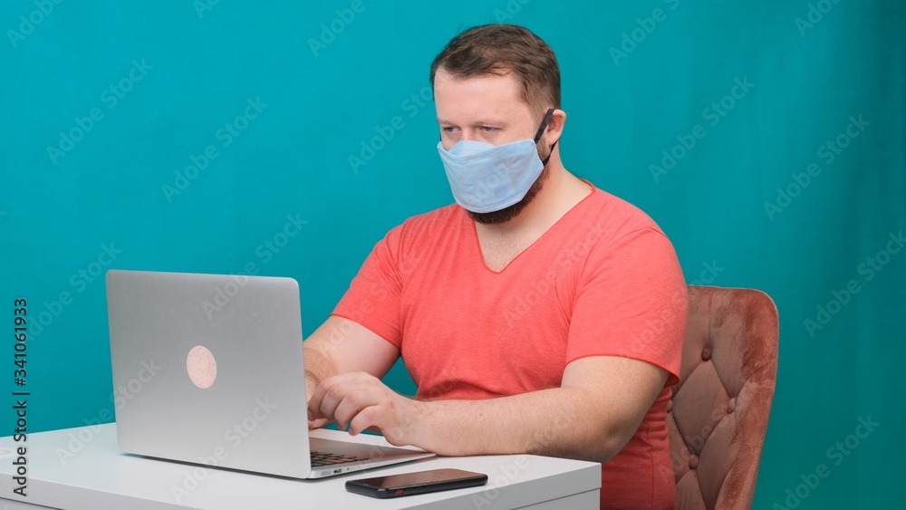 Caucasian adult bearded man works at home. Lifestyle concept photo with copy space. picture with a handsome guy who uses a protective mask.