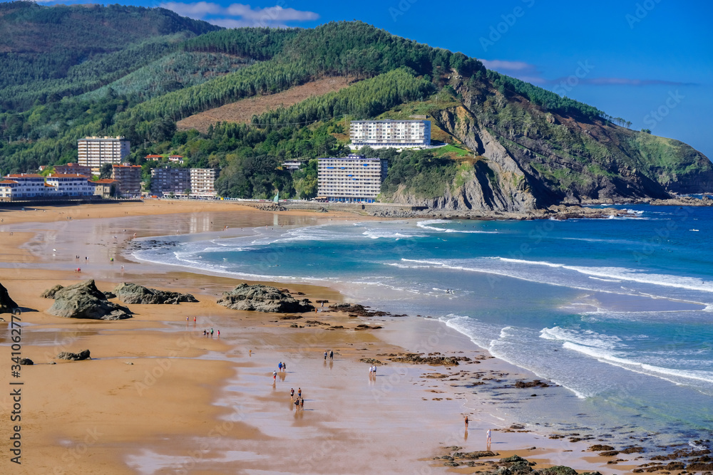 View of the beach of Bakio town. People walk on the sand at low tide. Near Bilbao and Gaztelugatxe, Basque Country, Northern Spain