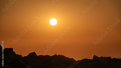 Amazing Sunset or Sunrise With Sun Over Dark Mountain Silhouette. Sunset in the orange sky