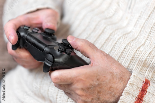 Close-up of senior hand holding video game controller .