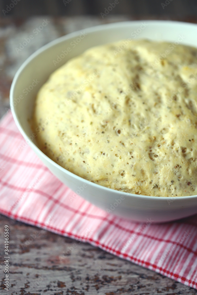 Yeast dough in a bowl. Homemade dough with herbs for bread or pizza. Baking at home. Yeast dough in a bowl. Homemade dough with herbs for bread or pizza. Baking at home.