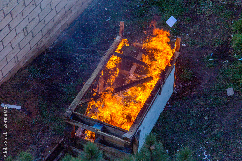 Fire coils over a burnt building. A pile of coals at the site of a burnt shed. Bright flames, flying ashes of a burning wooden building during a fire Fire coils over a burnt building. A pile of coals at the site of a burnt shed. Bright flames, flying ashes of a burning wooden building during a fire