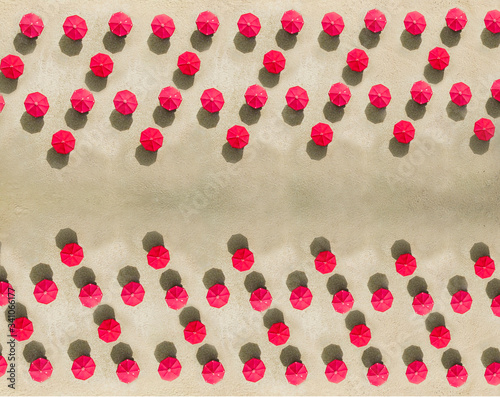 Aerial view of arrangement of red beach umbrellas on sandy beach