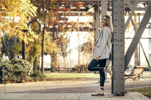 Portrait of fashionable young woman leaning against steel girder in autumn