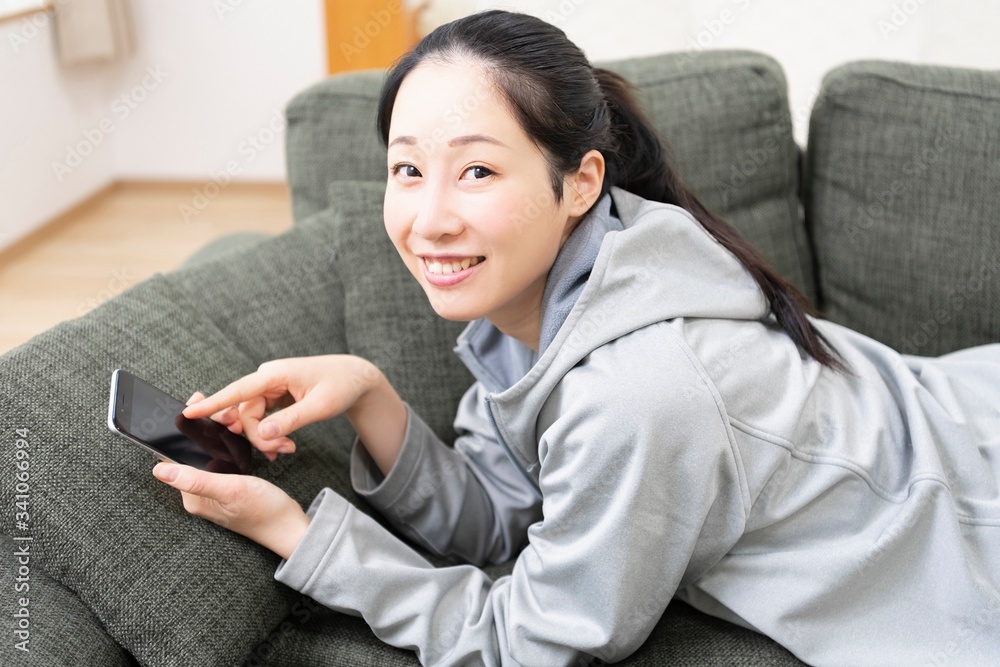 Obraz premium ソファーでスマホを使う女性