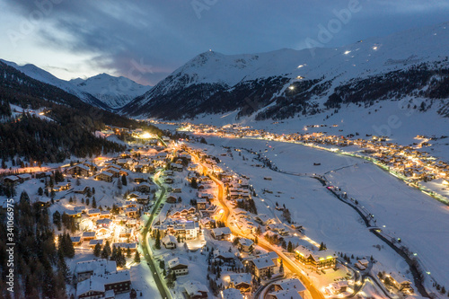 Italy, Province of Sondrio, Livigno, Aerial view of illuminated town in Italian Alps at dusk