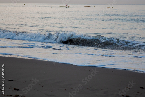 Kleine Welle am Strand bei Sonnenaufgang mit einem flachen Meer am Hintergrund