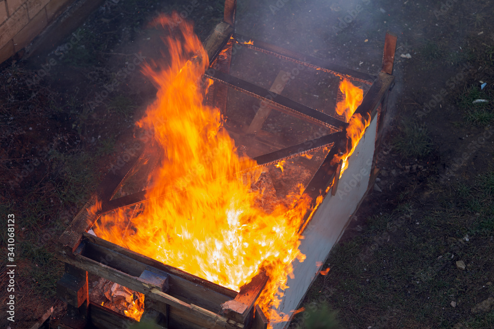 Fire coils over a burnt building. A pile of coals at the site of a burnt shed. Bright flames, flying ashes of a burning wooden building during a fire Fire coils over a burnt building. A pile of coals at the site of a burnt shed. Bright flames, flying ashes of a burning wooden building during a fire