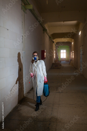 employee in a suit sprays  room from infection © solstizia