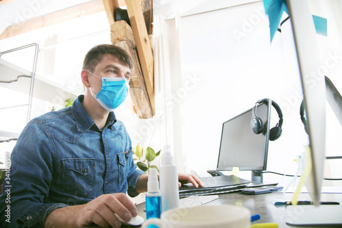 Young man in a protective mask in office or in home office. Man in the office wear mask to prevent corona virus. Protection virus and business concept.