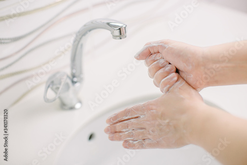 Woman washes her hands by surgical hand washing method. She washes his hands for at least 20 seconds. He washes his thumb.