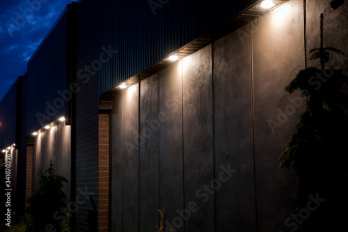 Large pot lights illuminating a concrete wall with bricks at twilight. Illuminated blank building wall in the dark.