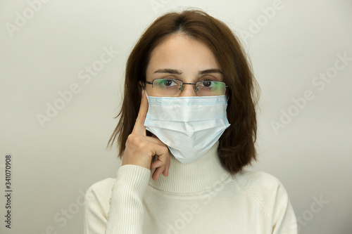 Young woman in glasses and a medical mask is thinking