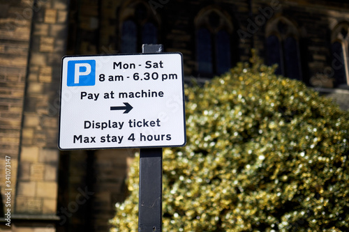 Parking information sign with green hedge background