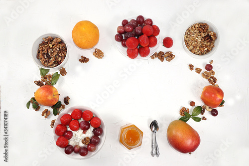 Fototapeta Naklejka Na Ścianę i Meble -  Strawberry yogurt, granola, cottage cheese, honey, mango, strawberries and grapes on a light table. The concept of healthy and natural food. Useful breakfast, food for children, selective focus,