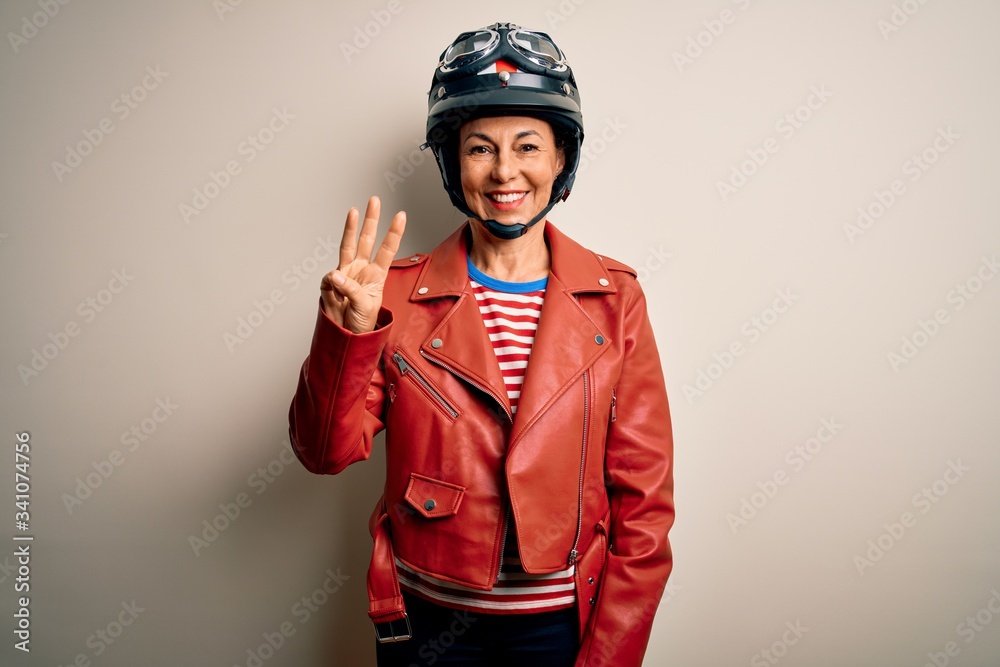 Middle age motorcyclist woman wearing motorcycle helmet and jacket over white background showing and pointing up with fingers number three while smiling confident and happy. Middle age motorcyclist woman wearing motorcycle helmet and jacket over white background showing and pointing up with fingers number three while smiling confident and happy.