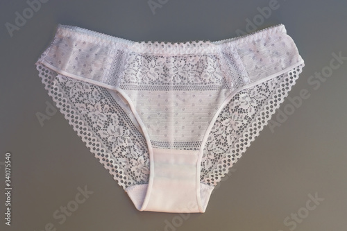 White lace panties on a gray background. Women's briefs made of cotton with lace. Sexy lingerie top view.