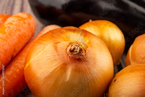 Juicy ripe onions, ripe eggplant and orange carrots on a wooden background. Close up.