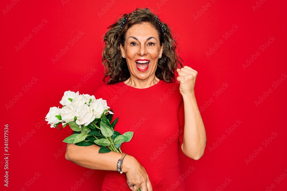 Middle age senior woman holding romantic bouquet of white roses over red background screaming proud and celebrating victory and success very excited, cheering emotion Middle age senior woman holding romantic bouquet of white roses over red background screaming proud and celebrating victory and success very excited, cheering emotion