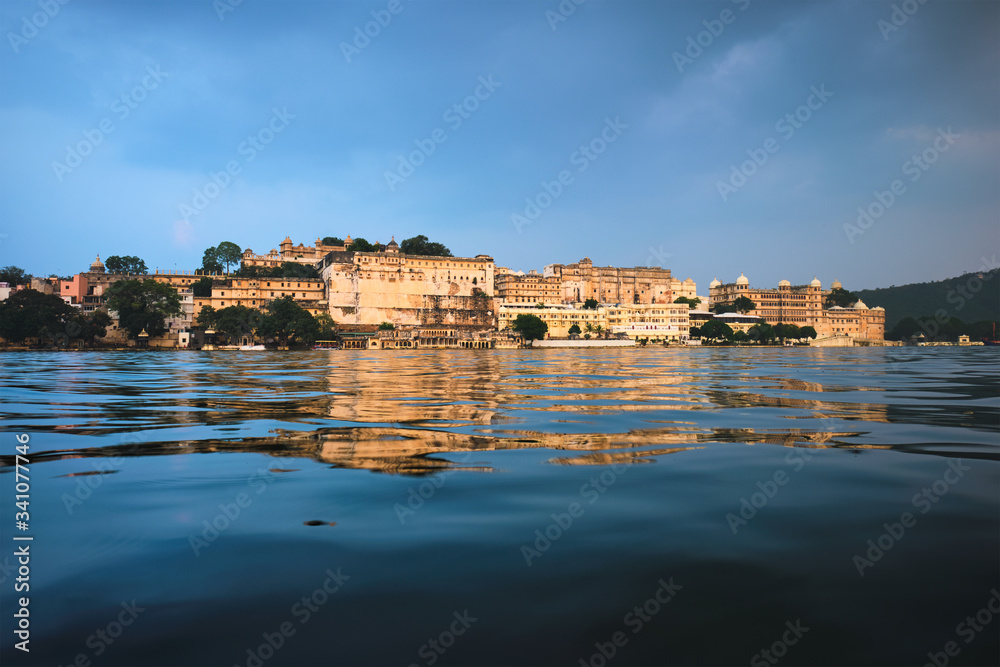 View of famous romantic luxury Rajasthan indian tourist landmark - Udaipur City Palace on sunset with cloudy sky - surface level view. Udaipur, Rajasthan, India