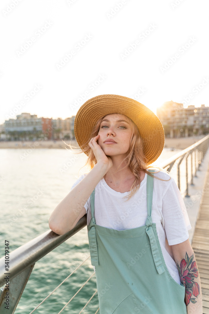 Young woman spending a day at the seaside, standing on bridge