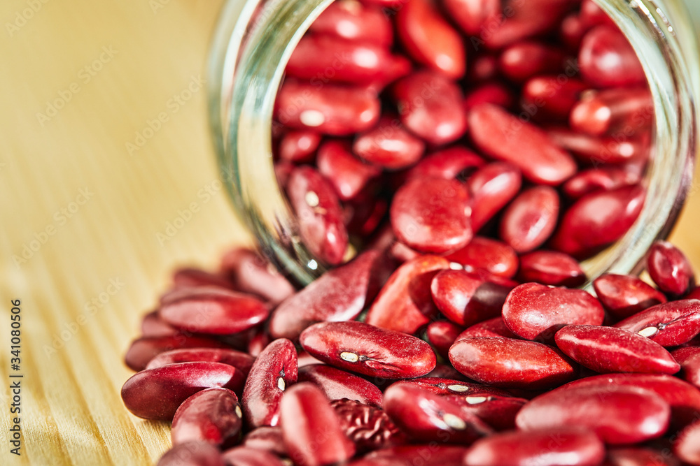Red beans seeds spilled out of a glass jar on a wooden background. Close up Red beans seeds spilled out of a glass jar on a wooden background. Close up