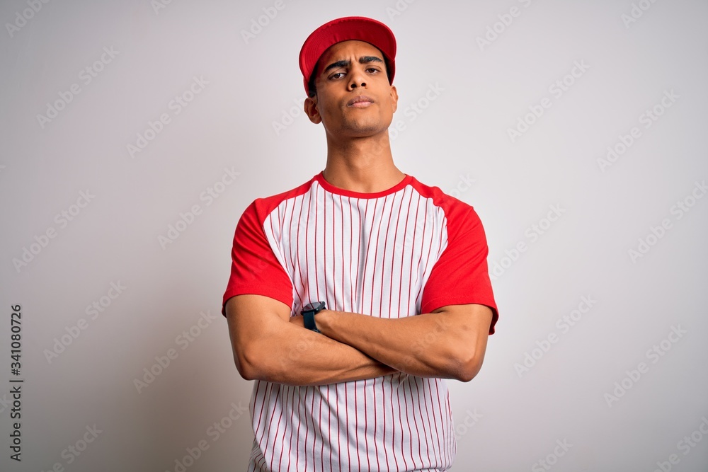 Young handsome african american sportsman wearing striped baseball t-shirt and cap skeptic and nervous, disapproving expression on face with crossed arms. Negative person. Young handsome african american sportsman wearing striped baseball t-shirt and cap skeptic and nervous, disapproving expression on face with crossed arms. Negative person.
