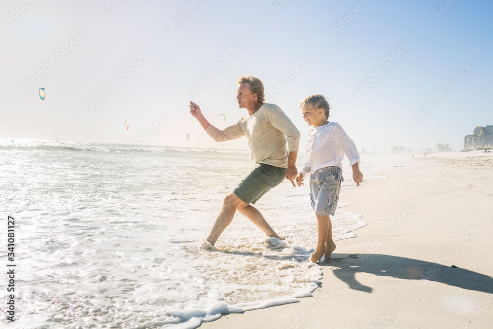 Father having fun with his son on the beach, throwing stones Father having fun with his son on the beach, throwing stones
