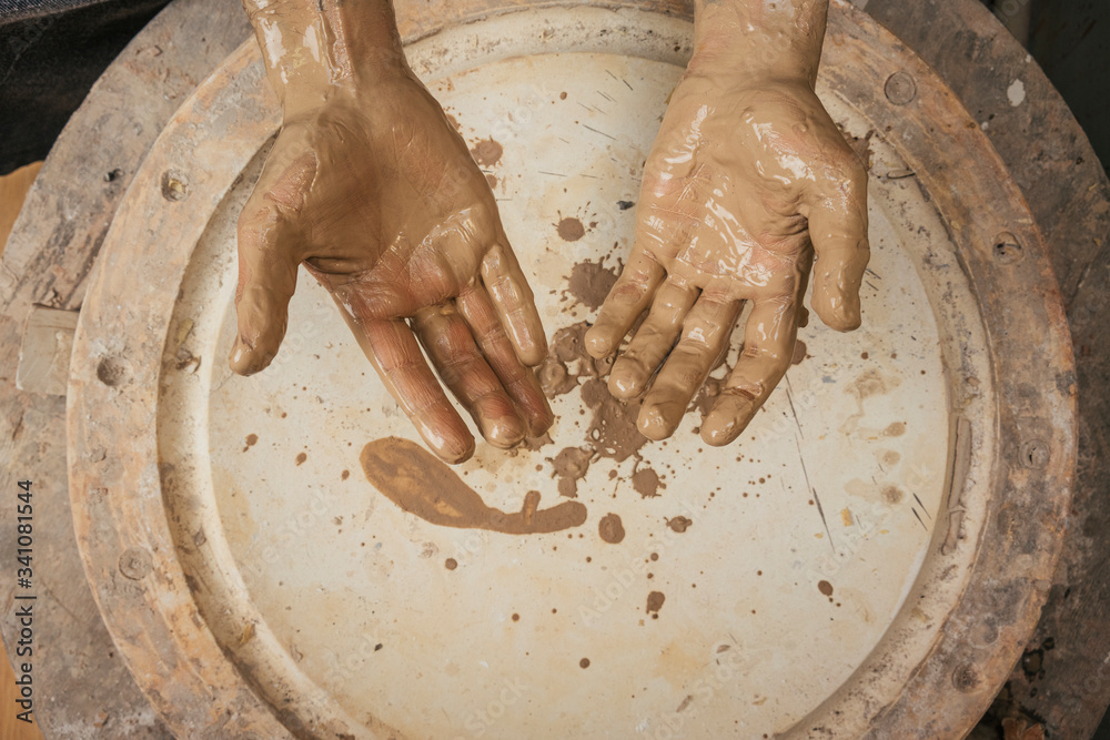Close-up of muddy hands of a potter in workshop