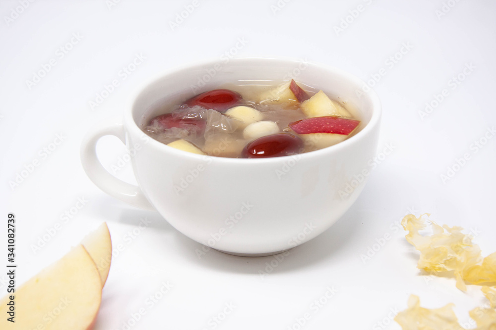 A bowl of white fungus soup with red apple, lotus seeds and red dates. A bowl of white fungus soup with red apple, lotus seeds and red dates.