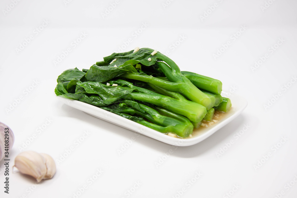 a plate of green gai lan (Chinese brocolli) with minced garlic a plate of green gai lan (Chinese brocolli) with minced garlic