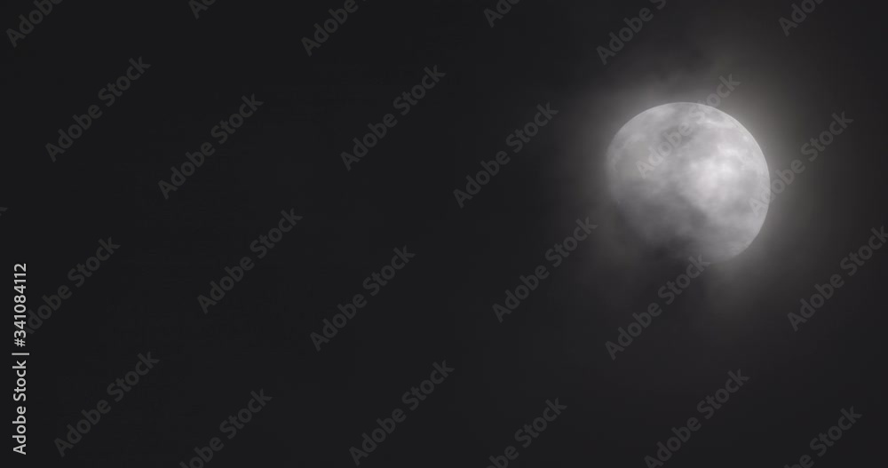 Bright Moon with Clouds Covering It Against the Dark Sky
