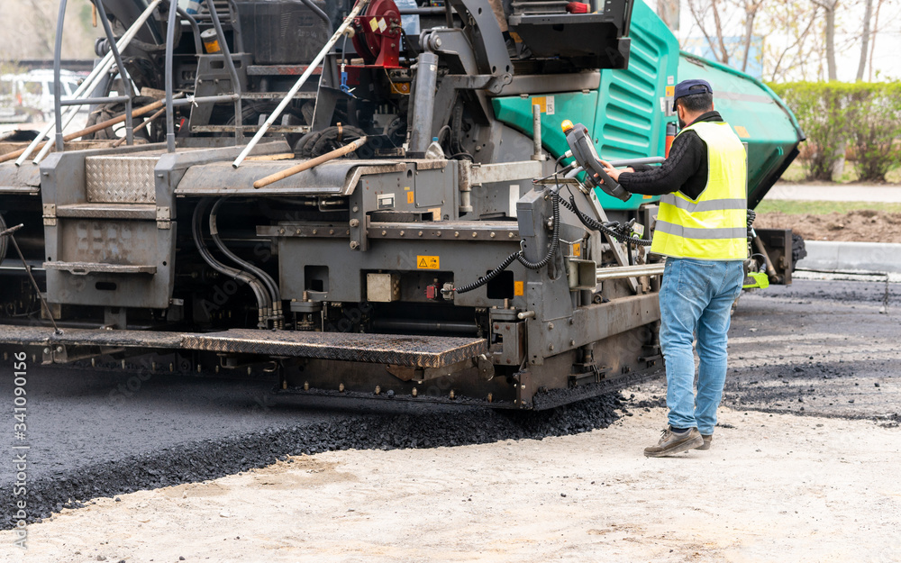 The specialist adjusts the paver before laying the adjacent pavement The specialist adjusts the paver before laying the adjacent pavement