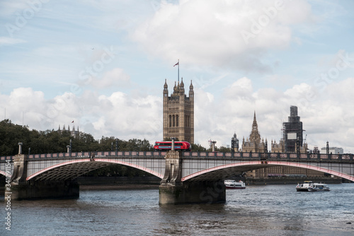 red double decker bus going over bridge in front of london tower