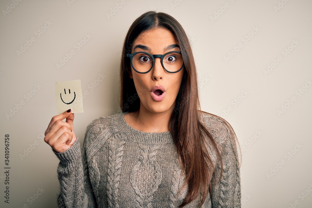 Young beautiful brunette woman wearing glasses holding paper with smile ...