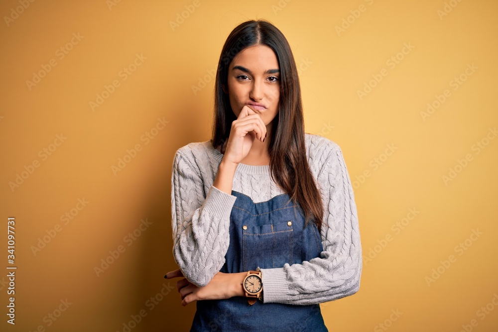 Young beautiful baker woman wearing apron uniform cooking over yellow background thinking looking tired and bored with depression problems with crossed arms. Young beautiful baker woman wearing apron uniform cooking over yellow background thinking looking tired and bored with depression problems with crossed arms.