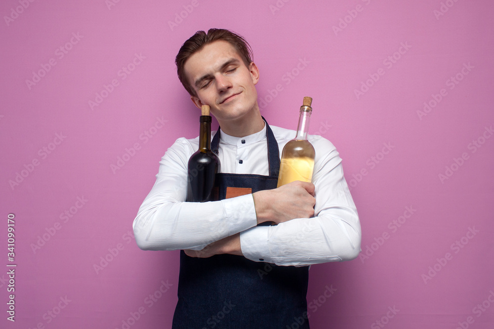 professional young handsome waiter in uniform hugs two bottles of red and white wine on a pink background, concept love of alcohol professional young handsome waiter in uniform hugs two bottles of red and white wine on a pink background, concept love of alcohol