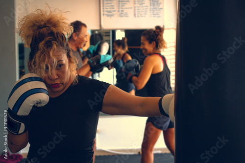 Fototapeta Naklejka Na Ścianę i Meble -  Woman practicing boxing with blue and white gloves in a gym