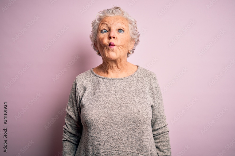 Senior beautiful woman wearing casual t-shirt standing over isolated pink background making fish face with lips, crazy and comical gesture. Funny expression. Senior beautiful woman wearing casual t-shirt standing over isolated pink background making fish face with lips, crazy and comical gesture. Funny expression.