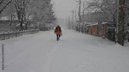 HOMBRE CAMINANDO EN CALLE CON NIEVE Y NEVANDO PUEBLO RUMANÍA NEVANDO