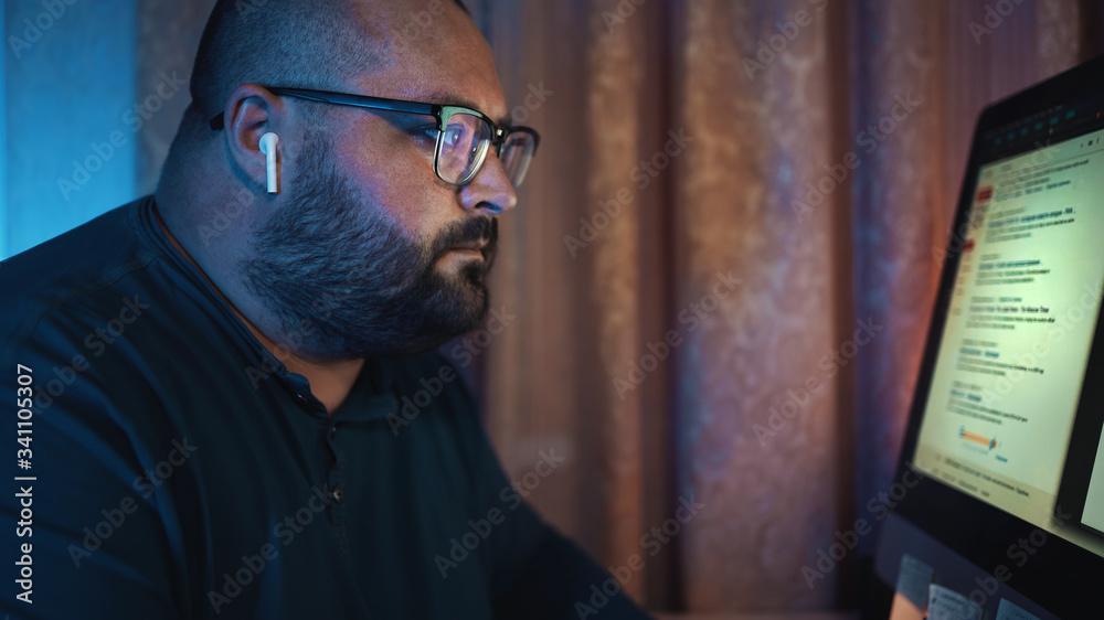 Distant work, man in glasses working at computer at night, freelancer at home. Distant work, man in glasses working at computer at night, freelancer at home.