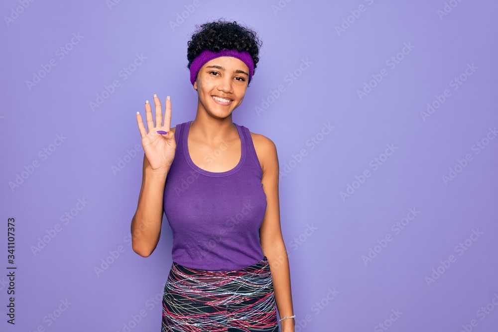 Beautiful african american afro woman wearing casual sportswear over purple background showing and pointing up with fingers number four while smiling confident and happy. Beautiful african american afro woman wearing casual sportswear over purple background showing and pointing up with fingers number four while smiling confident and happy.