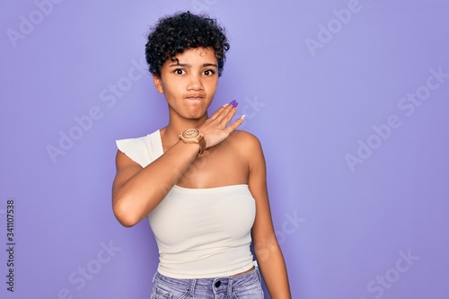 Young beautiful african american afro woman wearing casual t-shirt over purple background cutting throat with hand as knife, threaten aggression with furious violence