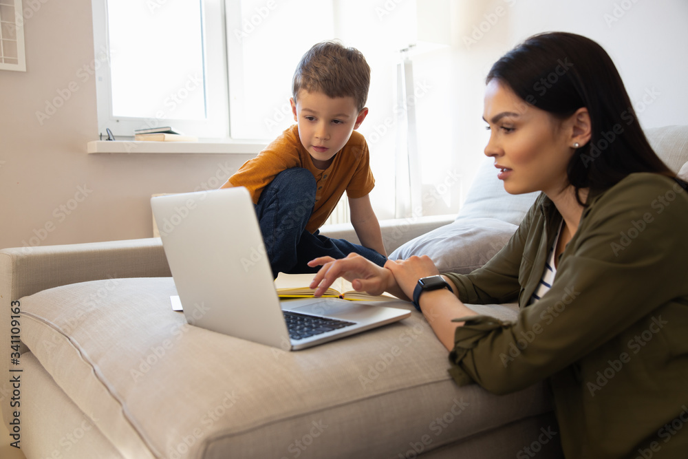 Cute little boy and his mother using laptop at home - obrazy, fototapety, plakaty 