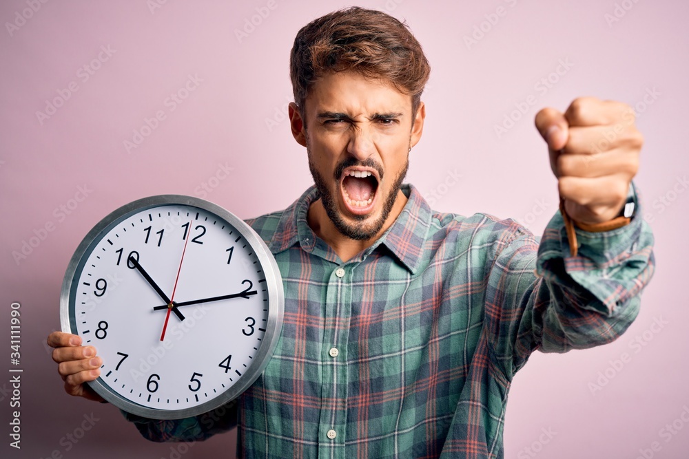 Young man with beard doing countdown using big clock over isolated pink background annoyed and frustrated shouting with anger, crazy and yelling with raised hand, anger concept Young man with beard doing countdown using big clock over isolated pink background annoyed and frustrated shouting with anger, crazy and yelling with raised hand, anger concept