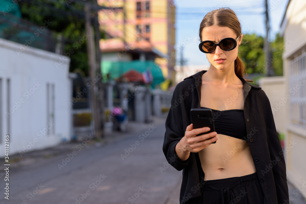 Fototapeta premium Portrait of young beautiful woman in the city streets outdoors