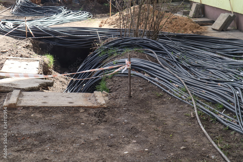 Black electrical wires go underground on a construction site. Industrial power supply. Black electrical wires go underground on a construction site. Industrial power supply.