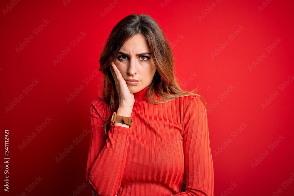 Young beautiful brunette woman wearing casual turtleneck sweater over red background thinking looking tired and bored with depression problems with crossed arms. Young beautiful brunette woman wearing casual turtleneck sweater over red background thinking looking tired and bored with depression problems with crossed arms.